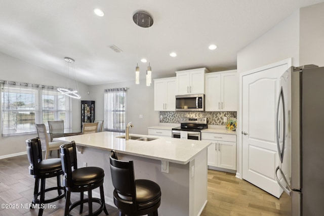 kitchen featuring sink, white cabinetry, decorative light fixtures, an island with sink, and stainless steel appliances