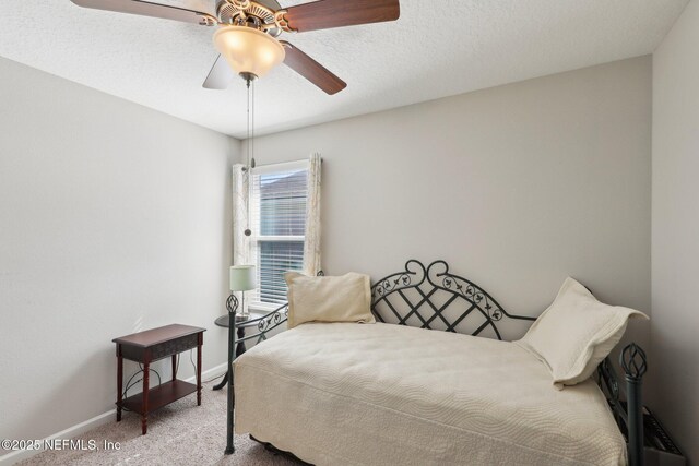 carpeted bedroom with ceiling fan and a textured ceiling