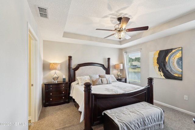 bedroom with light colored carpet, a textured ceiling, ceiling fan, and a tray ceiling