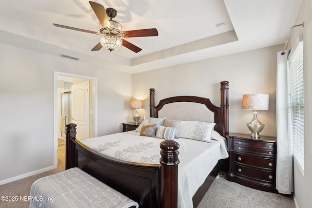 carpeted bedroom with a tray ceiling and ceiling fan