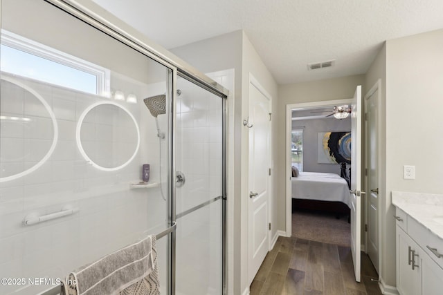 bathroom featuring a shower with door, vanity, wood-type flooring, and a textured ceiling