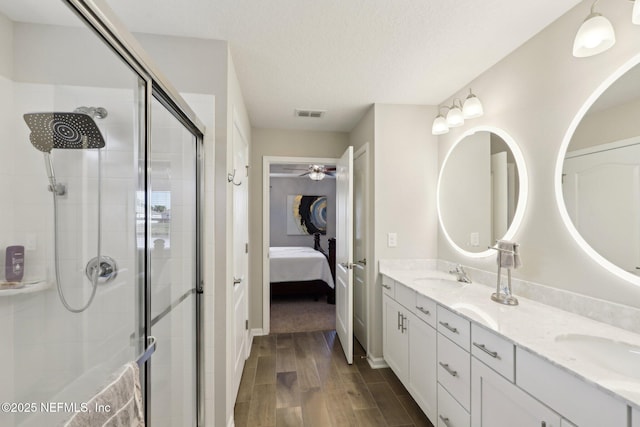 bathroom with vanity, ceiling fan, a textured ceiling, and a shower with shower door