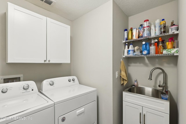 washroom featuring cabinets, washer and clothes dryer, sink, and a textured ceiling