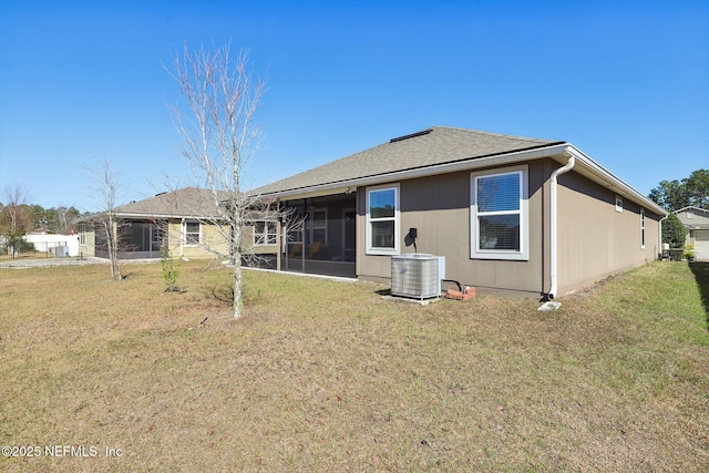 back of house featuring central air condition unit, a sunroom, and a lawn