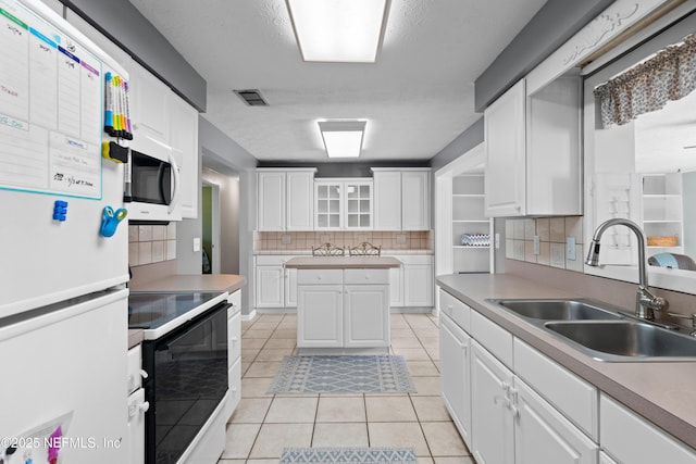 kitchen with white appliances, white cabinets, light countertops, a sink, and light tile patterned flooring