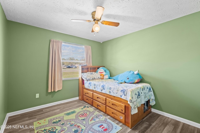 bedroom featuring dark wood-style floors, ceiling fan, a textured ceiling, and baseboards