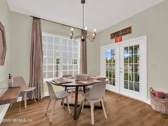 dining room with wood-type flooring, an inviting chandelier, and french doors