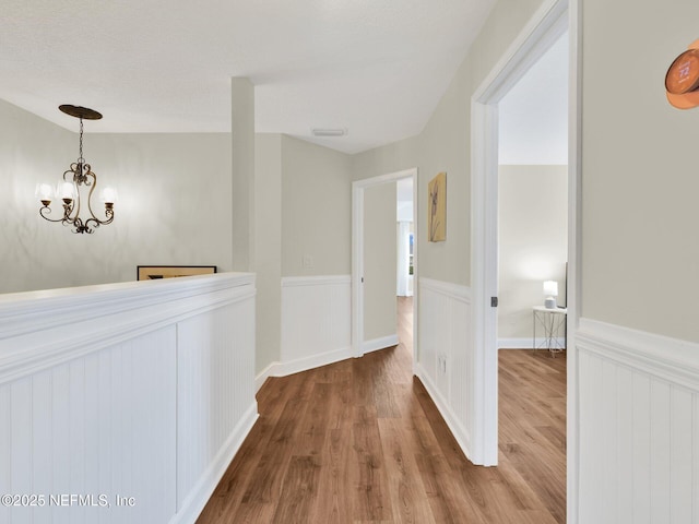 corridor featuring an inviting chandelier and hardwood / wood-style floors