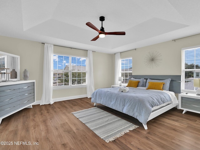 bedroom featuring ceiling fan, wood-type flooring, and a raised ceiling