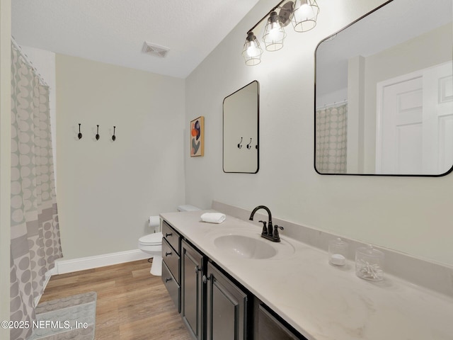 bathroom with hardwood / wood-style flooring, vanity, toilet, and a textured ceiling