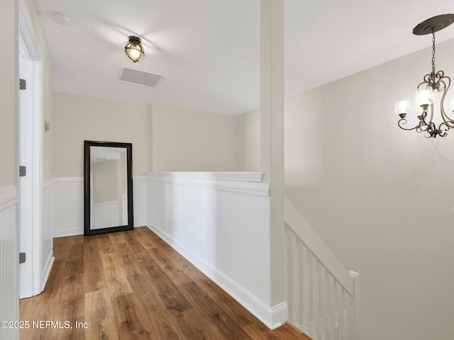 corridor with hardwood / wood-style flooring and a chandelier