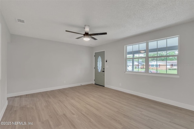 spare room with ceiling fan, a textured ceiling, and light wood-type flooring