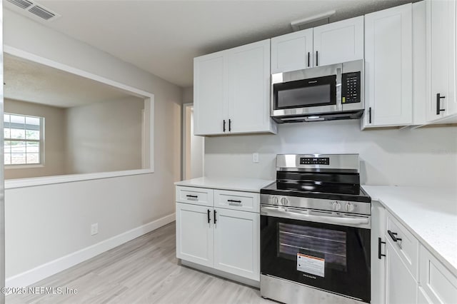 kitchen featuring stainless steel appliances, white cabinets, and light wood-type flooring