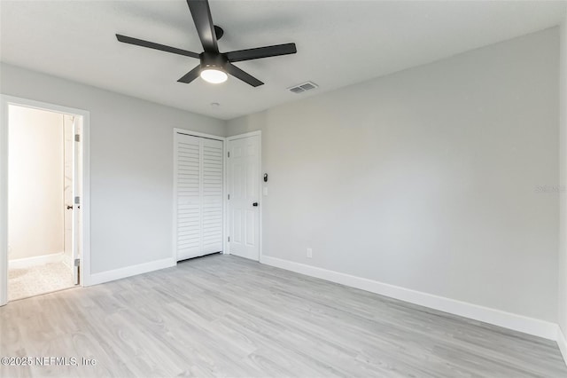 unfurnished bedroom with ensuite bathroom, ceiling fan, light wood-type flooring, and a closet