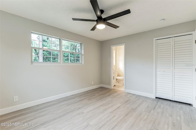 unfurnished bedroom featuring ceiling fan, ensuite bath, light wood-type flooring, and a closet