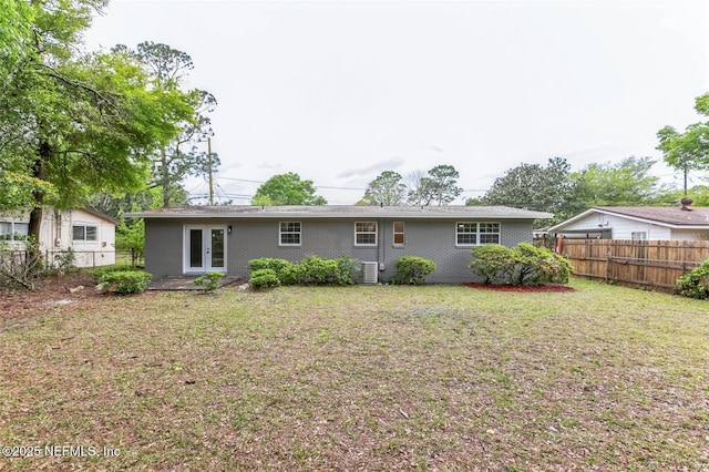 back of property with cooling unit, a lawn, and french doors