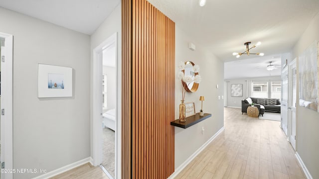 corridor featuring a notable chandelier and light hardwood / wood-style flooring