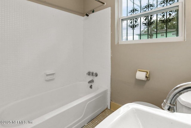 bathroom with tile patterned floors, washtub / shower combination, and toilet