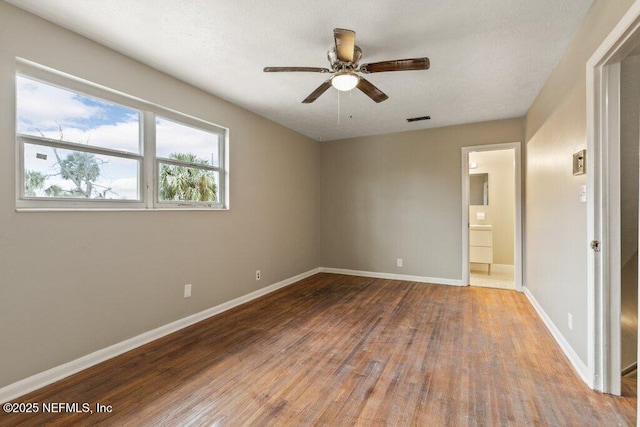 unfurnished bedroom with wood-type flooring, ensuite bathroom, and ceiling fan