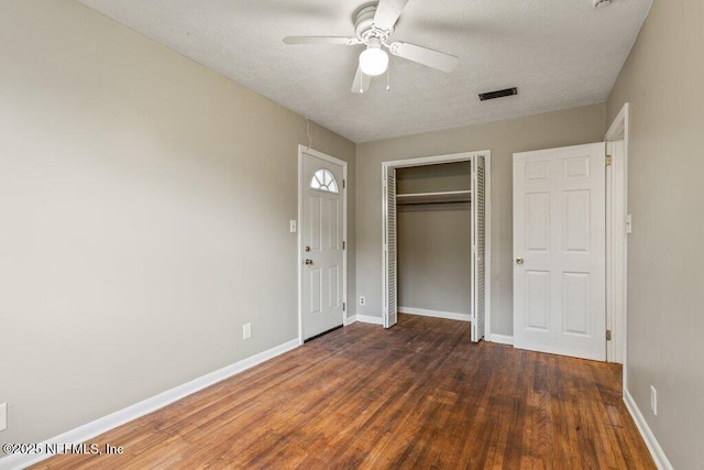 unfurnished bedroom featuring dark wood-type flooring, a closet, and ceiling fan