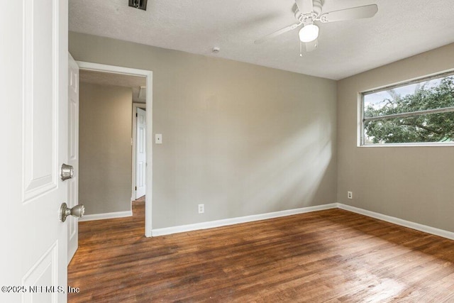 empty room with a textured ceiling, dark hardwood / wood-style floors, and ceiling fan