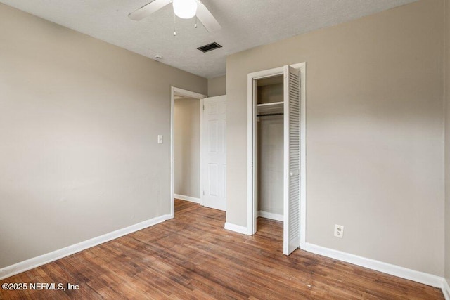 unfurnished bedroom with wood-type flooring, ceiling fan, and a closet