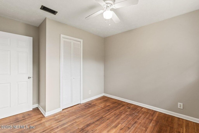 unfurnished bedroom with ceiling fan, wood-type flooring, and a closet