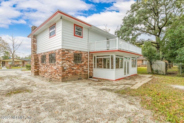 rear view of house with a sunroom and a balcony