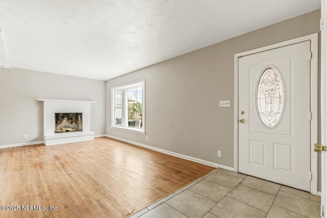 foyer featuring a brick fireplace, a textured ceiling, and light wood-type flooring