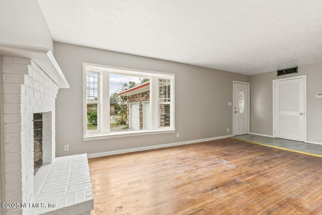 unfurnished living room with a fireplace, light hardwood / wood-style floors, and a textured ceiling