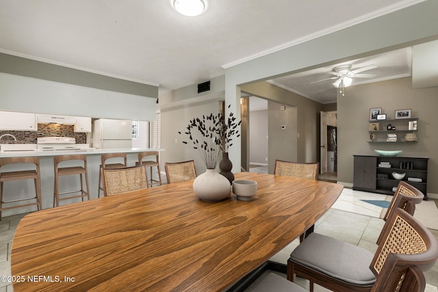 dining space with ornamental molding, sink, light tile patterned floors, and ceiling fan