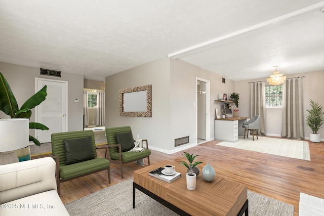 living room featuring a chandelier, a textured ceiling, and light hardwood / wood-style flooring