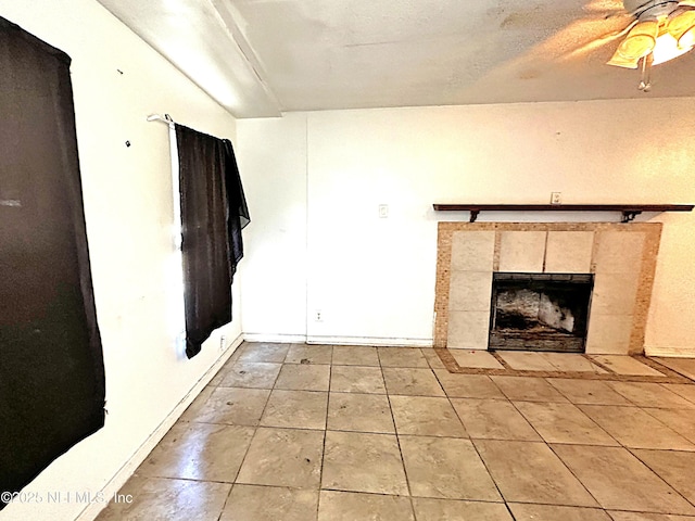 unfurnished living room featuring ceiling fan, a tile fireplace, and light tile patterned floors