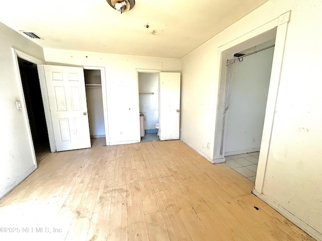 unfurnished bedroom with ensuite bath and light hardwood / wood-style flooring