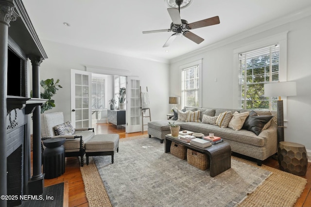 living room with french doors, crown molding, ceiling fan, a fireplace, and hardwood / wood-style floors