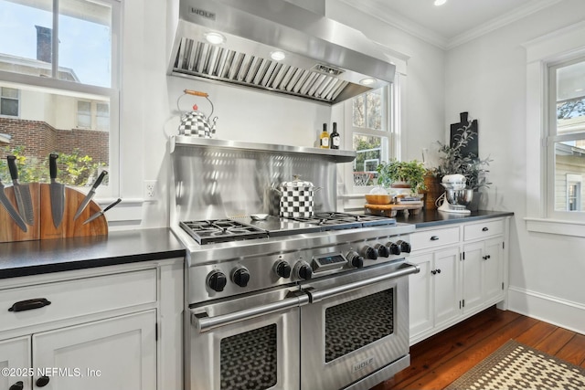 kitchen with white cabinetry, double oven range, ornamental molding, dark wood-type flooring, and wall chimney exhaust hood