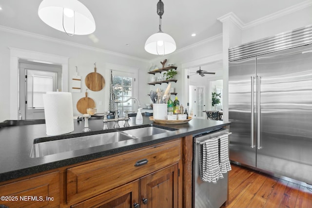 kitchen featuring sink, crown molding, hanging light fixtures, stainless steel appliances, and light wood-type flooring