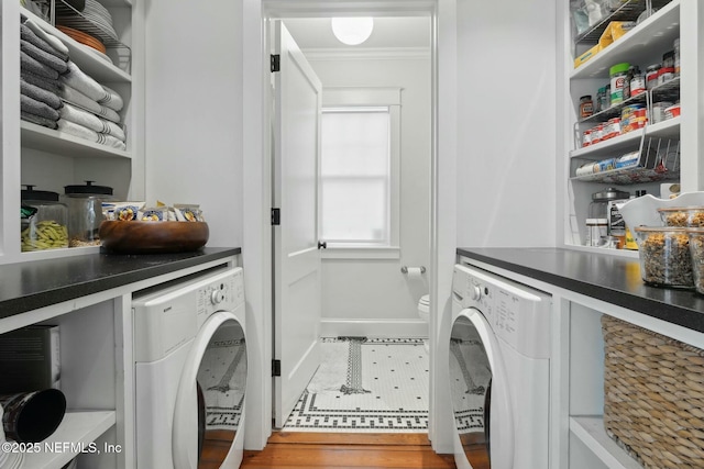 clothes washing area featuring ornamental molding, washer and clothes dryer, and wood-type flooring