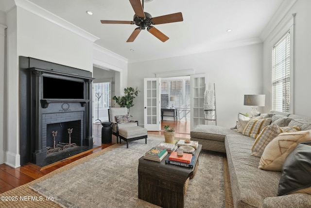 living room with french doors, crown molding, ceiling fan, a fireplace, and hardwood / wood-style floors