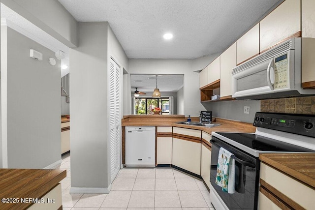 kitchen with white appliances, tasteful backsplash, light tile patterned floors, a textured ceiling, and a sink