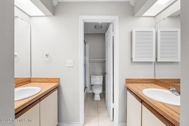 bathroom featuring two vanities, a sink, toilet, and tile patterned floors