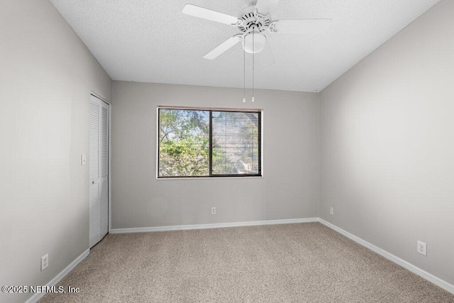 empty room featuring carpet, ceiling fan, a textured ceiling, and baseboards