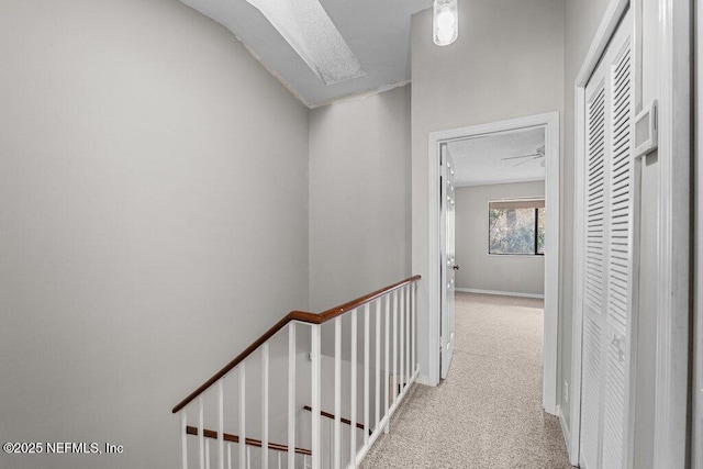 hall with baseboards, carpet flooring, and an upstairs landing