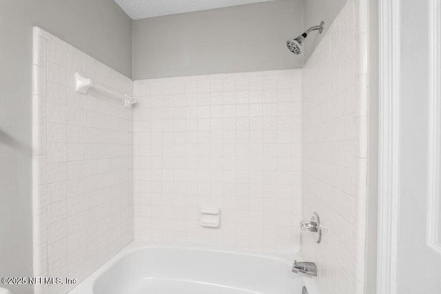 full bathroom with a textured ceiling and bathing tub / shower combination