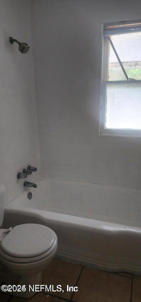 bathroom with tile patterned flooring, shower / bathtub combination, and toilet