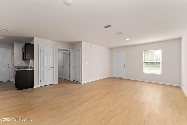 unfurnished living room with sink and light wood-type flooring