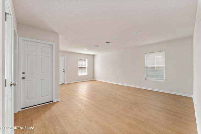 empty room with a textured ceiling and light hardwood / wood-style floors