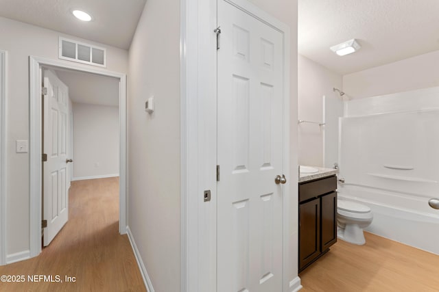 full bathroom with vanity, wood-type flooring, a textured ceiling, and toilet