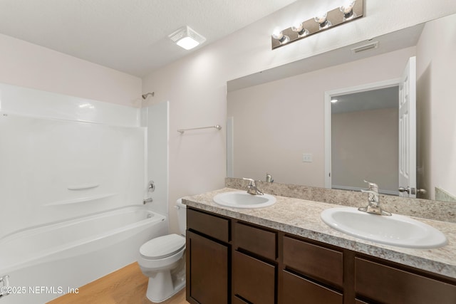 full bathroom with bathing tub / shower combination, vanity, wood-type flooring, a textured ceiling, and toilet