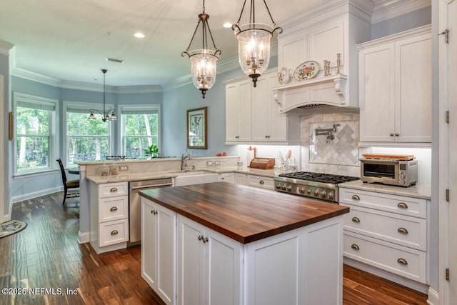 kitchen featuring butcher block countertops, an inviting chandelier, decorative light fixtures, dishwasher, and a kitchen island